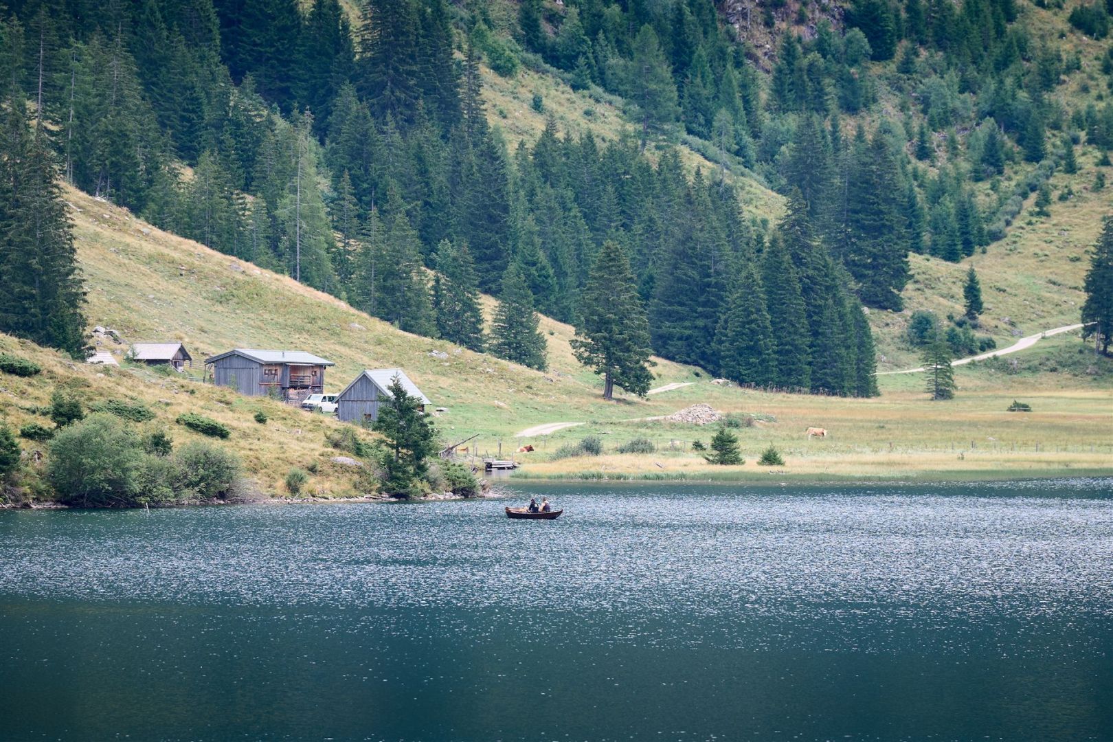 Ein Boot auf dem Riesachsee, im Hintergund stehen mehrere Hütten am Ufer.