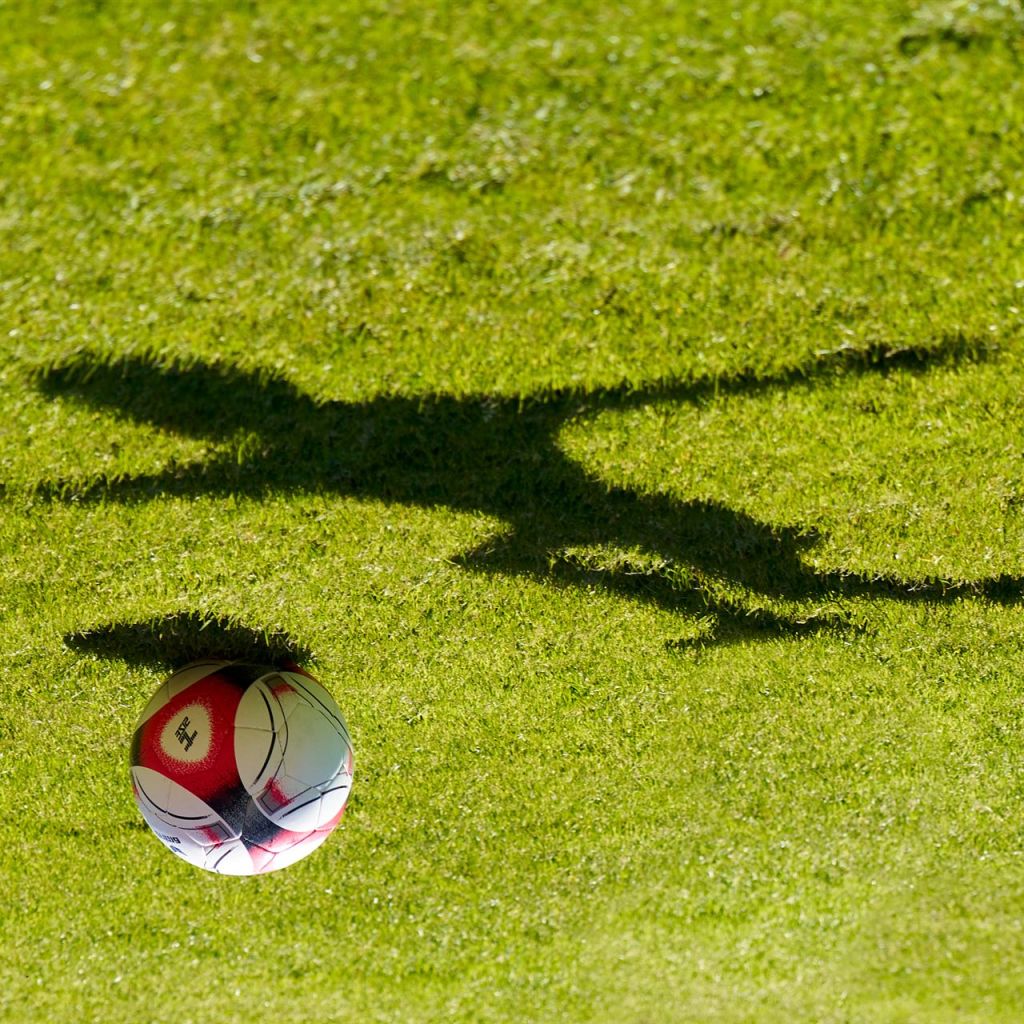 Schatten eines Fußballspielers springt über den Ball