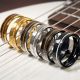Sechs Ringe mit einer Einlage aus einer Gitarrensaite stehen zwischen den Saiten einer Gitarre
