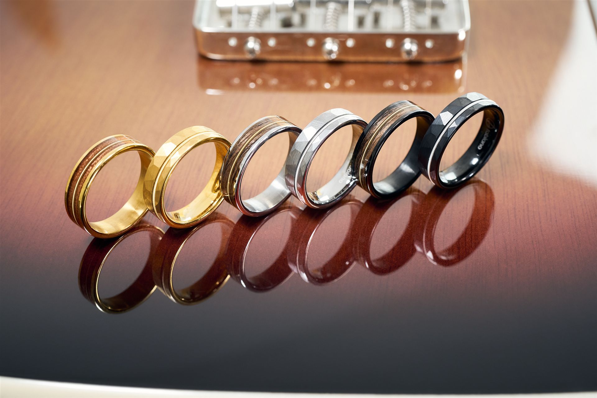 Sechs Ringe mit einer Einlage aus einer Gitarrensaite stehen schräg nebeneinander am Korpus einer Gitarre